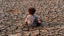 Ein Kind sitzt in Honduras auf ausgetrocknetem Boden - eine Folge des Klimawandels