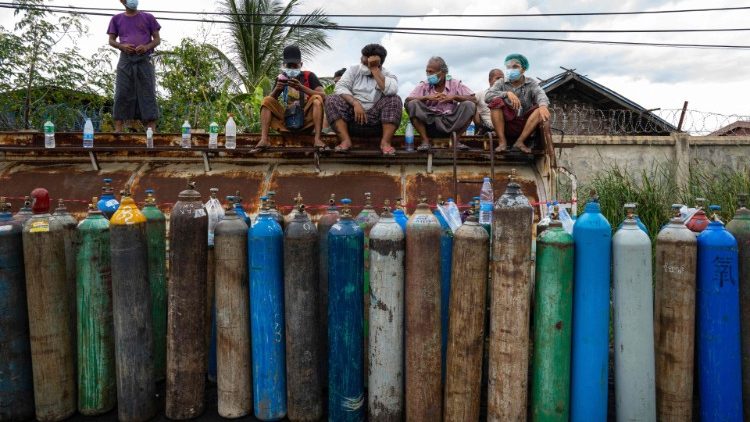 Des Birmans attendent le remplissage de bouteilles d'oxygène dans une rue de Mandalay, le 13 juillet 2021