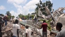 People search through the rubble of a building in Les Cayes, Haiti