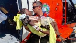 Membro da Guarda Costeira dos Estados Unidos transporta criança ferida para hospital em Porto Príncipe