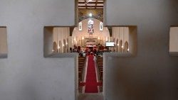 Kirchenraum, durch eine kreuzförmige Öffnung betrachtet