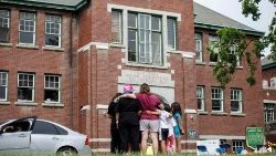 A family stands in front of the former Kamloops Indian Residential School