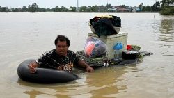 Vietnamita transporta mercadorias em local inundado por enchentes nos arredores de Phnom Penh, em 27 de outubro de 2021, após fortes chuvas de monções. (Foto de TANG CHHIN Sothy / AFP)