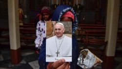 Refugiado mostra uma imagem do Papa Francisco na Igreja franciscana da Assunção em Lesbos