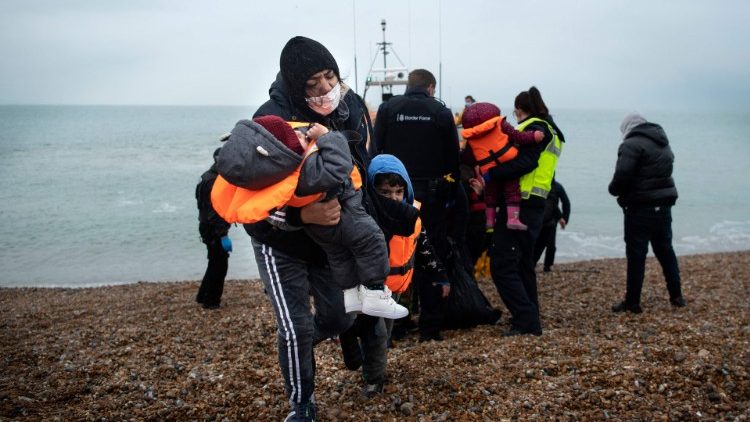 A migrant carries her children after a rescue operation in the English Channel
