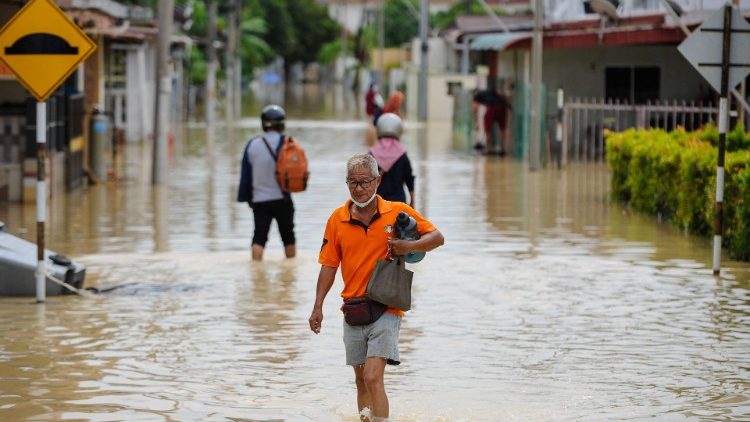 Residents wade through floodwaters in Batu Berendam in Malaysia