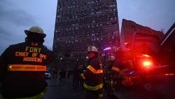 Firefighters work outside an apartment building after a deadly fire in the Bronx