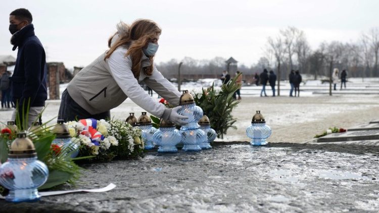 A young woman places candles at the International Monument to the Victims of Fascism at the Memorial and Museum Auschwitz-Birkenau