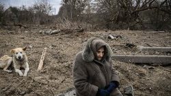 Una donna siede in un luogo colpito dai bombardamenti in Ucraina