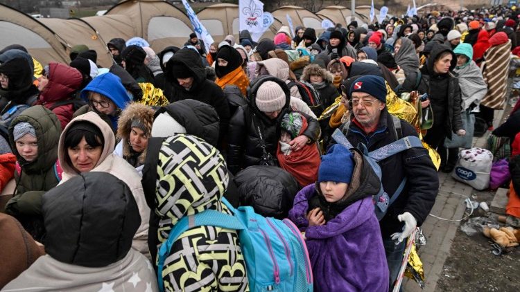 Refugees stand in line in the cold as they wait to be transferred to a train station after crossing the Ukrainian border into Poland, at the Medyka border crossing in Poland, on March 7