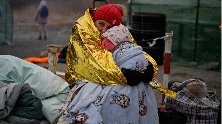 Una refugiada de Ucrania abraza a su hijo en medio de la desolación de la guerra.