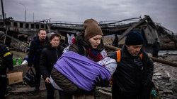 Una mujer con su bebé cruza un puente destruido mientras huyen de la ciudad de Irpin, al noroeste de Kiev, el 7 de marzo de 2022.