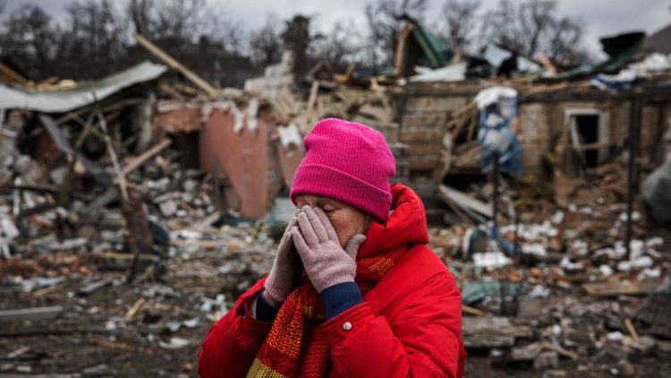 A woman reacts in front of a house that was damaged in an aerial bombing in the city of Irpin, northwest of Kyiv
