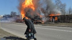 Um idoso numa estrada de Kharkiv em chamas causas por tiros de artilharia russa