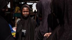 Uma mulher caminha pelo mercado no campo de M'Berra usando seu tradicional vestido Fulani em Bassikonou. O campo de M'Berra, no sudeste da Mauritânia, é um dos maiores da África Ocidental que acolhe refugiados, fugindo de violências multifacetadas em Mopti e Timbuktu (norte) centrais do Mali, violências atribuídas a grupos jihadistas, forças malianas e os elementos do Grupo Wagner. (Foto de GUY PETERSON)
