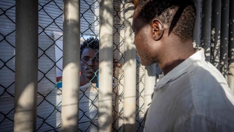 A migrant talks to a man through a fence in a temporary centre for migrants and asylum seekers in Melilla