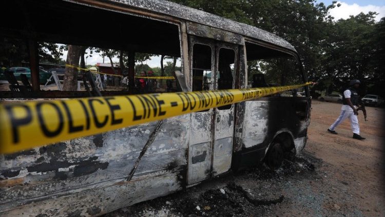 A police officer walks beside a burnt prison vehicle in Abuja, Nigeria
