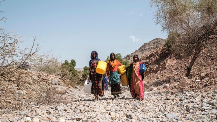Internally displaced women carry jerrycans in the makeshift camp where they are sheltered in Erebti, Ethiopia