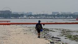 File photo of a man filming while walking past garbage on a beach in Manila.