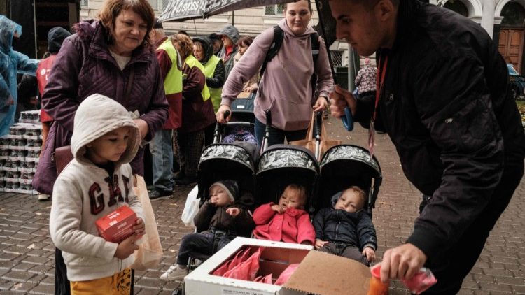 Ilyuashenko Tatyana (2ª D), 32 anos, mãe de quatro filhos, recebe alimentos durante sua distribuição para cerca de 3.000 pessoas pela filial local da Caritas Internationalis, uma organização de caridade católica, em Kharkiv, em 27 de setembro de 2022. (Foto de Yasuyoshi CHIBA / AFP)