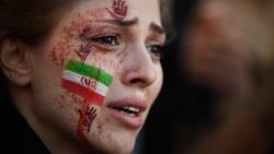 Une manifestante, portant un drapeau iranien et des mains rouges peints sur le visage, assiste à un rassemblement de soutien aux protestations iraniennes à Paris, le 9 octobre 2022, à la suite de la mort de l'iranienne Masha Amini en Iran.