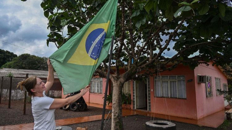 A resident of the municipality of Mercedes holds a flag outside of her home