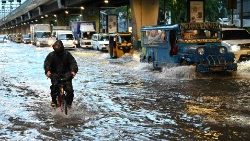 Vehicles pass along a flooded street in Manila following heavy rains brought about by a tropical storm