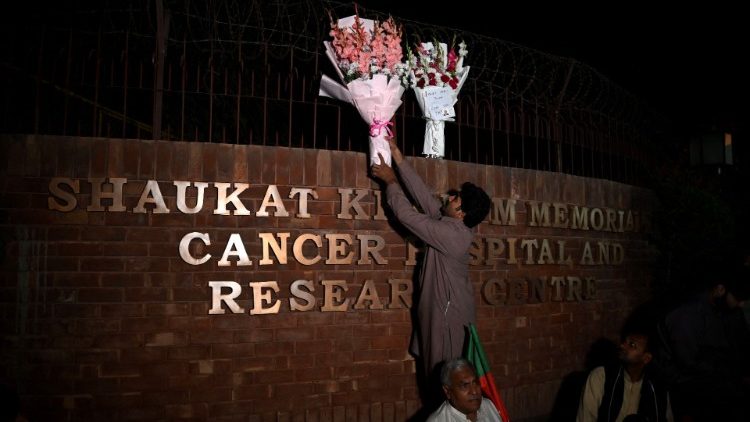 A supporter of Imran Khan places flowers outside the hospital where he is admitted after being shot