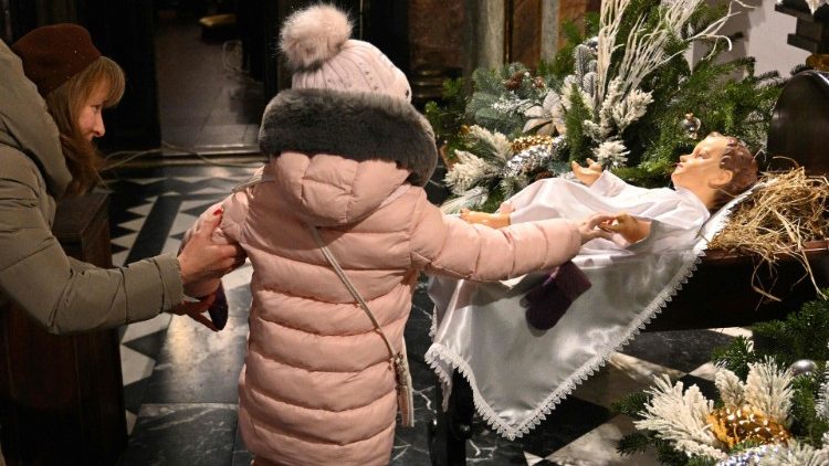Ucraina: una bambina prima della Messa di Natale (25 dicembre 2022, Afp).