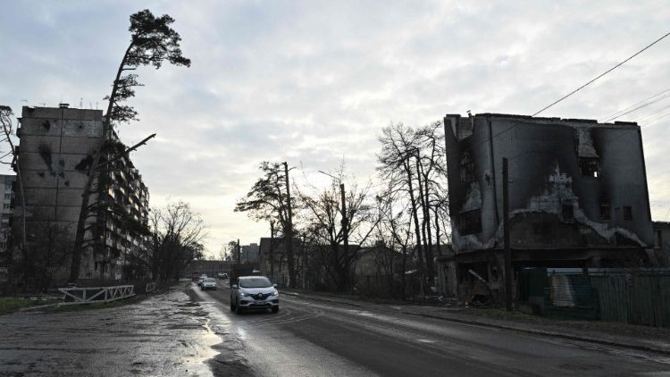 Carros passam por prédios residenciais fortemente danificados em Irpin, a noroeste de Kyiv, em 23 de dezembro de 2022, em meio à invasão russa da Ucrânia. (Foto de Genya SAVILOV / AFP)
