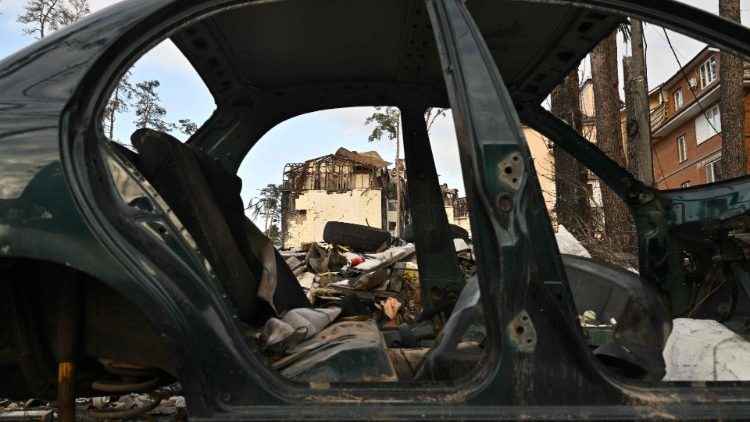 Esta fotografia tirada em 23 de dezembro de 2022 mostra edifícios residenciais fortemente danificados atrás de um carro destruído em Irpin, a noroeste de Kyiv, em meio à invasão russa da Ucrânia. (Foto de Genya SAVILOV / AFP)