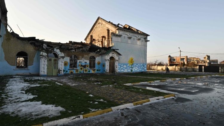 Pessoas passam por uma casa de cultura fortemente danificada em Irpin, a noroeste de Kyiv, em 23 de dezembro de 2022, em meio à invasão russa da Ucrânia. (Foto de Genya SAVILOV / AFP)