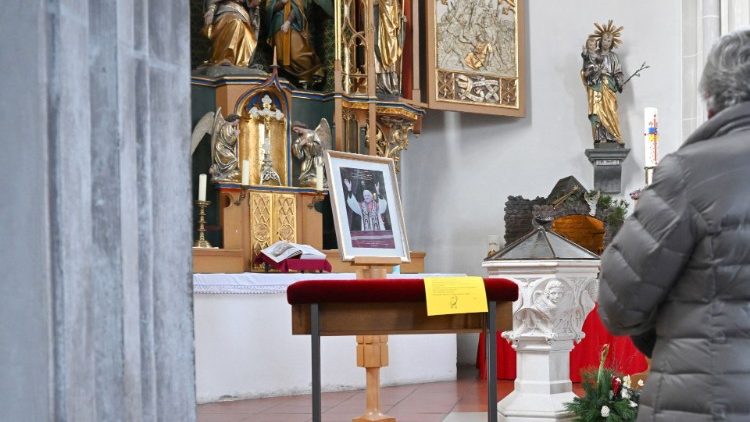A woman prays in front a picture of Benedict XVI in St. Oswald Church in his birthplace of Marktl, Germany
