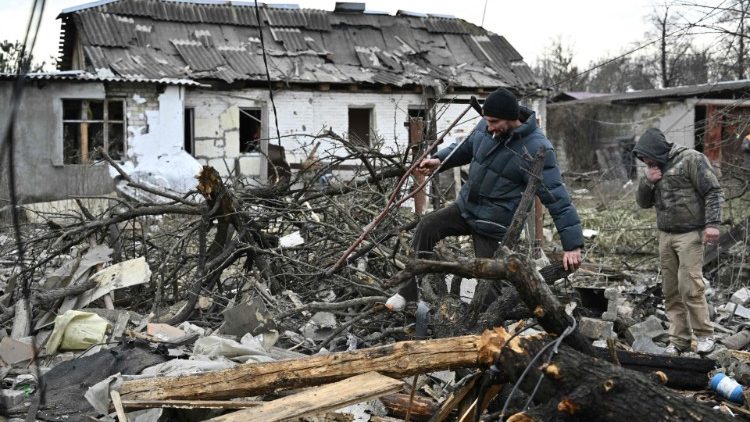Moradores locais caminham entre os escombros de casas destruídas por um ataque de míssil nos arredores de Kyiv, em 29 de dezembro de 2022, após um ataque de míssil russo à Ucrânia. - Ataques de mísseis russos atingiram a Ucrânia, inclusive em grandes cidades como Kyiv, Kharkiv e Lviv em 29 de dezembro, deixando pelo menos cinco pessoas feridas e cortando a eletricidade no oeste. (Foto de Genya SAVILOV / AFP)