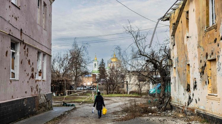 Um morador local passa por edifícios danificados na cidade de Izium, leste da Ucrânia, em 2 de janeiro de 2023. (Foto de Sameer Al-DOUMY / AFP)