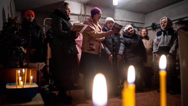 Ludzie celebrujący razem liturgię Bożego Narodzenia w piwnicy w miejscowości Czasiw Jar pod Bachmutem, 7 stycznia 2023