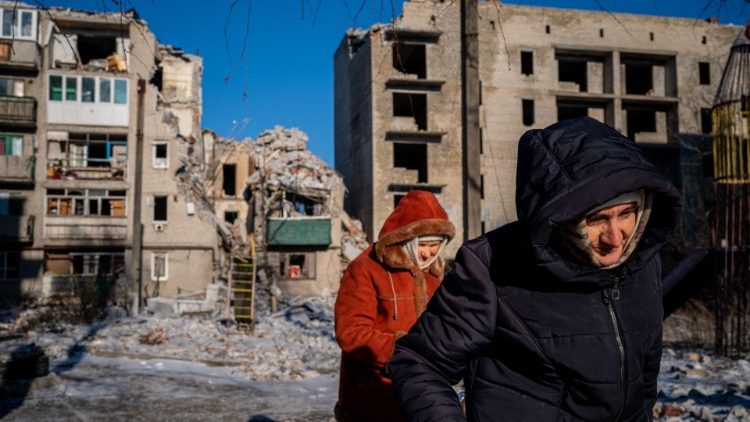 Idosos residentes locais passam por um prédio residencial destruído em Chasiv Yar, leste da Ucrânia, em 7 de janeiro de 2023, em meio à invasão russa da Ucrânia. - Enquanto a artilharia explodia do lado de fora e os caças sobrevoavam, os cristãos ortodoxos em uma cidade devastada do leste da Ucrânia realizaram um culto de Natal em um abrigo no porão em 7 de janeiro, prometendo não deixar a guerra arruinar o feriado. (Foto de Dimitar DILKOFF / AFP)