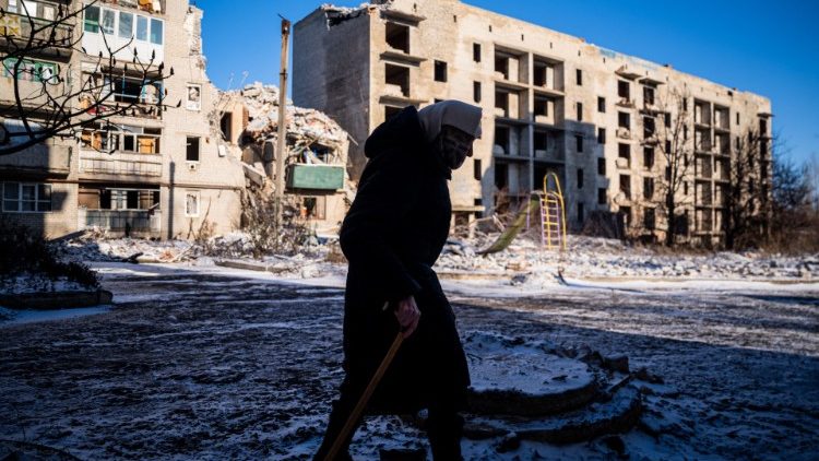 Idosa passa por um prédio residencial destruído em Chasiv Yar, leste da Ucrânia, em 7 de janeiro de 2023, em meio à invasão russa da Ucrânia.. (Foto de Dimitar DILKOFF / AFP)