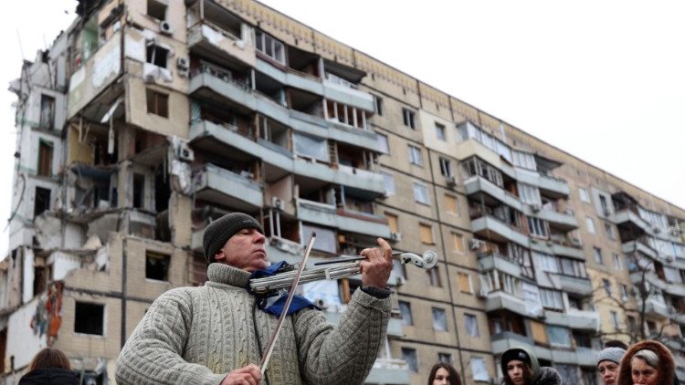 Um homem toca violino à margem de um serviço religioso realizado por residentes locais e moradores locais em frente ao prédio residencial na cidade ucraniana de Dnipro em 22 de janeiro de 2023, destruído como resultado de um ataque de míssil em 14 de janeiro.. (Photo by Anatolii STEPANOV / AFP)