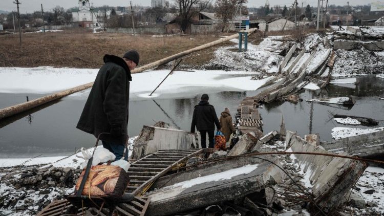 Pessoas caminham em uma ponte destruída para cruzar um canal em direção à área disputada em Bakhmut em 1º de fevereiro de 2023, em meio à invasão russa da Ucrânia. (Foto de YASUYOSHI CHIBA/AFP)