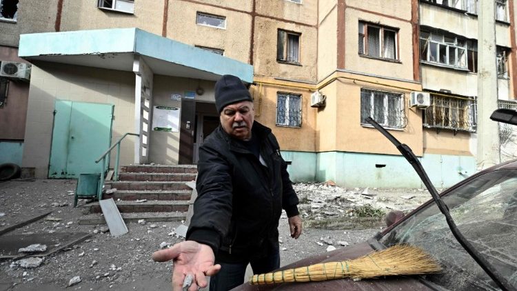 Um morador local mostra um fragmento em frente a um prédio residencial danificado após um ataque russo em Kherson em 3 de fevereiro de 2023, em meio à invasão russa da Ucrânia. (Foto de Genya SAVILOV / AFP)