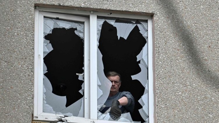 Um residente local remove o vidro quebrado de sua janela em um prédio residencial após um ataque russo em Kherson em 3 de fevereiro de 2023, em meio à invasão russa da Ucrânia. (Foto de Genya SAVILOV / AFP)