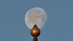 A lua, com a cúpula da Basílica de São Pedro e a cruz em primeiro plano, em 8 de fevereiro de 2023. (Foto de Alberto PIZZOLI/AFP)