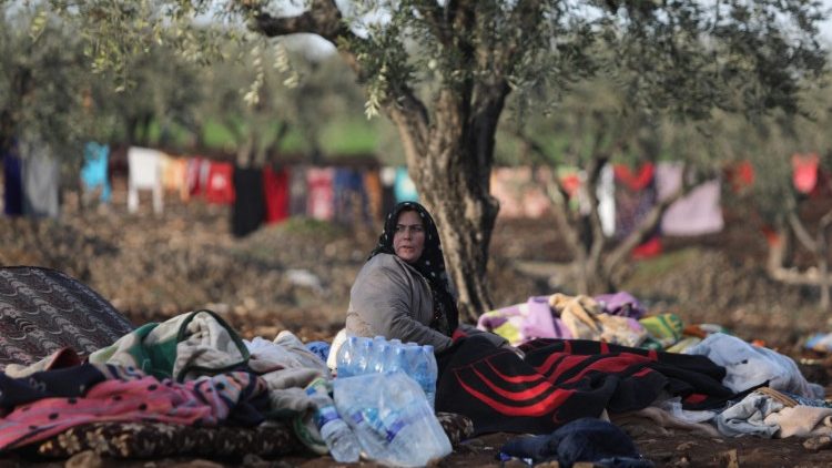 A woman huddles under blankets in nearby Syria