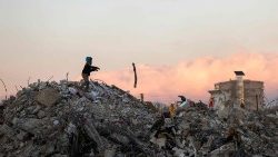 A Syrian boy stands atop a pile of rubble in Jableh