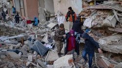 Una mujer busca a sus familiares entre los escombros de edificios derrumbados es escoltada, en Hatay, el 14 de febrero de 2023, tras el terremoto de magnitud 7,8 que sacudió el sureste del país.