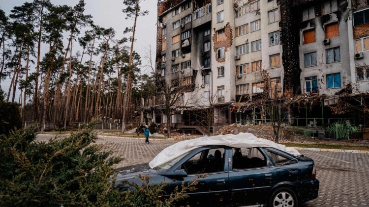Uma mulher passa por um prédio residencial no complexo residencial Irpinsky Lipky, que foi fortemente danificado durante combates entre tropas russas e ucranianas na cidade de Irpin, perto de Kiev, em 16 de fevereiro de 2023. (Foto de Dimitar DILKOFF / AFP)