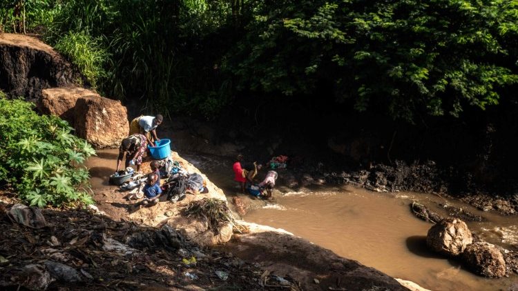 Women wash clothes in a contaminated river in Malawi