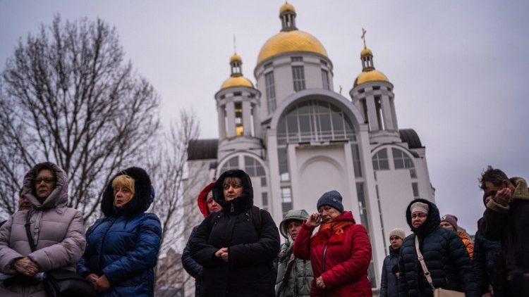 Ucraina, persone in preghiera davanti una chiesa a Bucha
