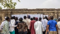 Devant un bureau de vote à Abuja, des citoyens cherchent leur nom sur la liste des votants. 